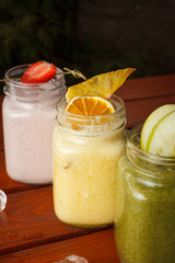 Close up view of different tastes of smoothies on a wooden table: strawberry, apple green, citrus and berries smoothies