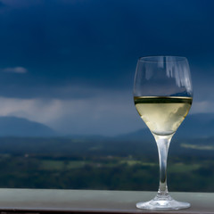A glass of white whine with mountains in the background and approaching rain