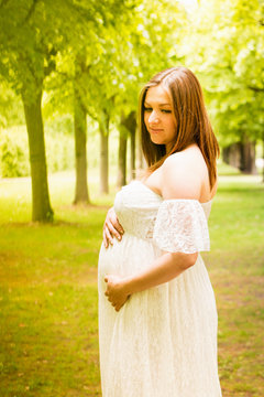 Happy pregnant woman posing over green natural background