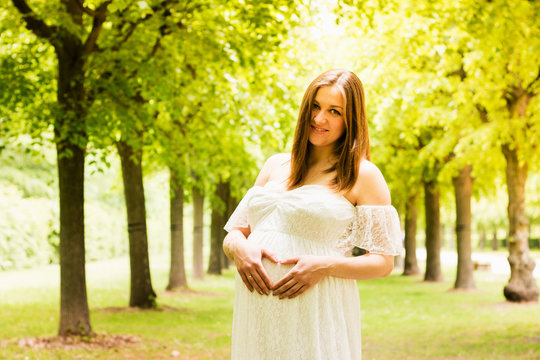 Happy pregnant woman posing over green natural background