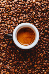 Roasted coffee beans with cup of espresso on dark background