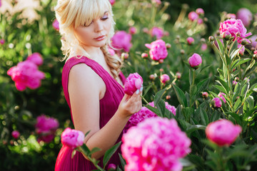 Obraz na płótnie Canvas Outdoor close up portrait of beautiful young woman with long blonde hair, makeup, posing in the blooming garden. Female spring fashion concept