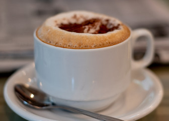 Cappuccino  at the cafe close-up side view, decorated with coccoa and cinamon 