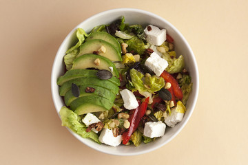 Bowl of an avocado salad with feta cheese and red bell pepper view from above. Close up.