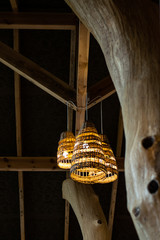 Handcraft lamp with weave pattern hanging from dark ceiling. Traditional handcraft made from wooden vine widely used for interior decoration and furniture.
