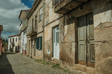 Old houses with cracked plaster wall in an alley with pedestrian