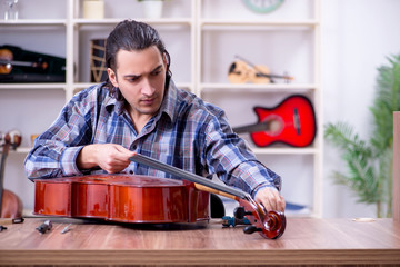 Young handsome repairman repairing cello