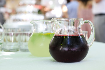 Jugs with fresh cold drinks on table