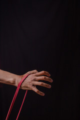 hand of a man exercising with stretching rubber stretching band on a black background in the studio training workout gym