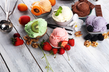 ice cream scoops of different colors and flavours with berries, nuts and fruits decoration on white...