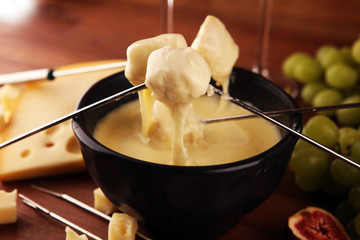 Gourmet Swiss fondue dinner on a winter evening with assorted cheeses on a board alongside a heated pot of cheese fondue