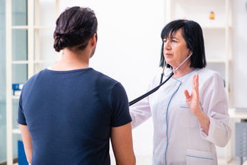 Young male patient visiting aged female doctor 