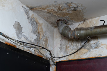 Old water leak on ceiling, water damaged plaster and pipe, utility services problem