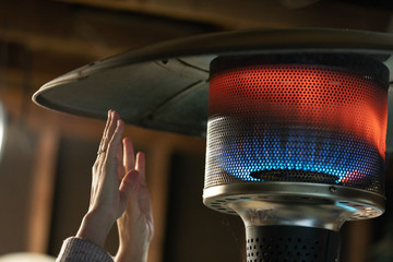 Hands warming close to the flames of propane patio heater