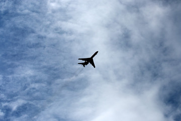 the plane flies across the blue sky