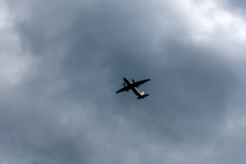 the plane flies across the blue sky