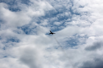 the plane flies across the blue sky