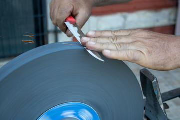 Knife sharpening hand and sanding machine close-up.