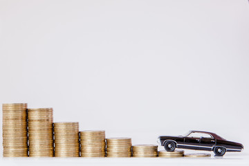 A black model of a car with coins in the form of a histogram on a white background. Concept of lending, savings, insurance.