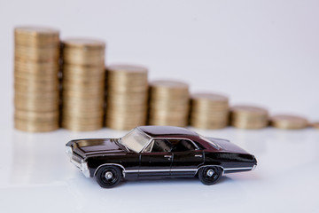A black model of a car with coins in the form of a histogram on a white background. Concept of lending, savings, insurance.