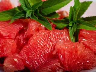 peeled grapefruit in a plate decorated with a sprig of peppermint