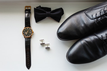 Composition of men's accessories. Expensive wristwatch, black classic butterfly, stylish cufflinks, leather classic shoes top view.