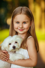 Little girl with a maltese puppy, outdoor summer