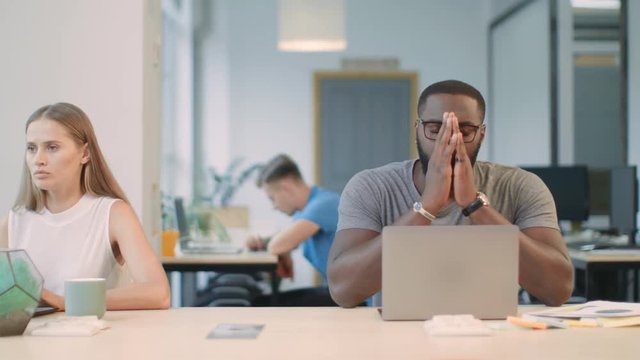 Upset man reading bad news on laptop computer at coworking space