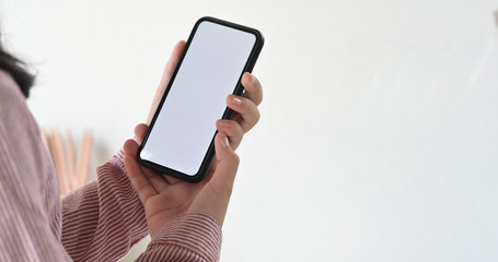 Image of hands holding black mock up mobile phone with blank screen