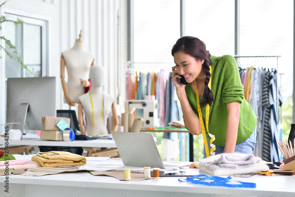 Wall mural young asian woman entrepreneur / fashion designer working in studio