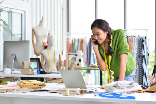 Young Asian woman entrepreneur / fashion designer working in studio