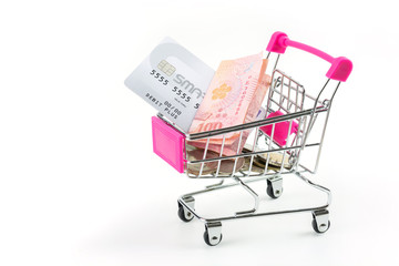 Credit cards and banknotes with thai currency coins in a small shopping cart on a white background.