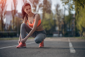 attractive brunette woman warm up and stretching in park at sunshine