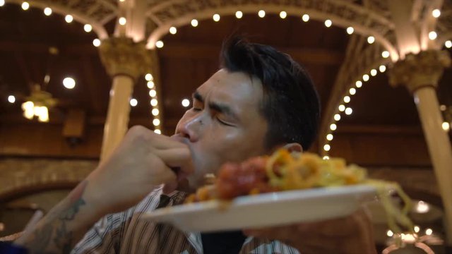 This video shows a sloppy and hungry asian man devouring a large plate full of food with his hands.