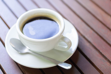 Closeup glass of hot americano coffee on wood table, selective focus, vintage tone