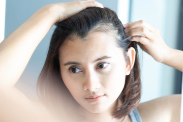 Woman looking reflection in the mirror serious hair loss problem for health care shampoo and beauty product concept