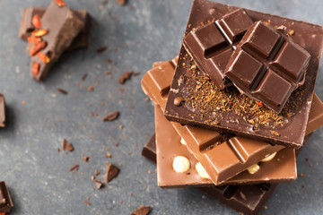Handmade chocolate bars with nuts and goji berry on a grey background
