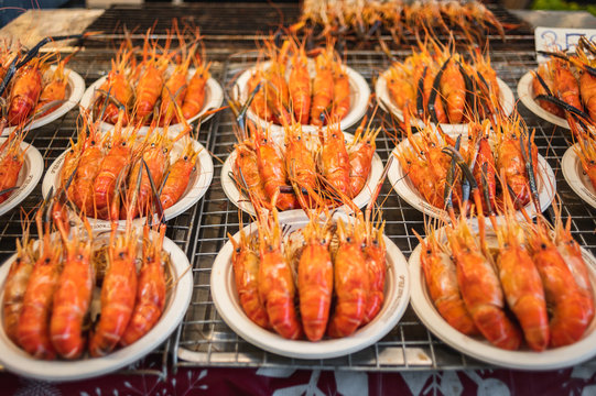 Street food in Bangkok, delivious looking cooked grilled prawn on paper plate.