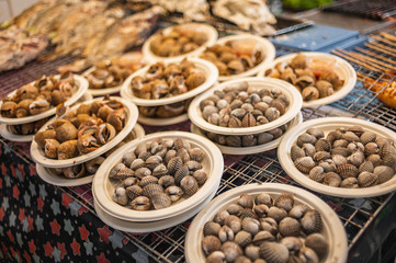 Street food in Bangkok, delicious looking cooked seashells and cockles on paper plate.