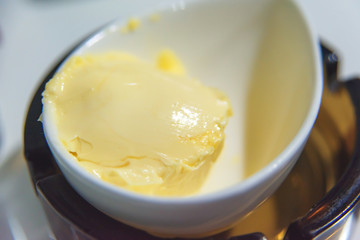 Butter in a white cup. Yellow butter for breakfast. Thawed butter for spreading on bread