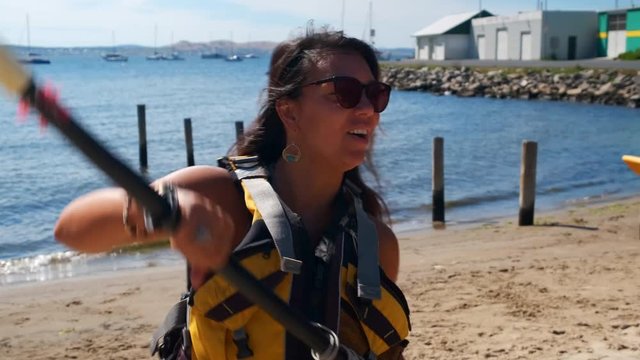 Slow motion close up of a young woman wearing life jacket mimicking paddling excited about the upcoming kayaking tour
