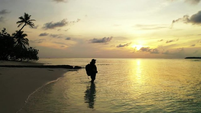 Young girl with a backpack enjoying the sunset on a beach in the Philippines