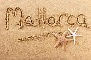 Mallorca majorca word written in sand on a sunny spanish summer beach with starfish holiday...