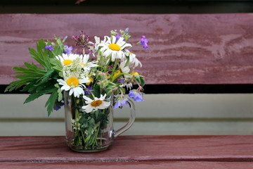 There is a cup with wild flowers on the table