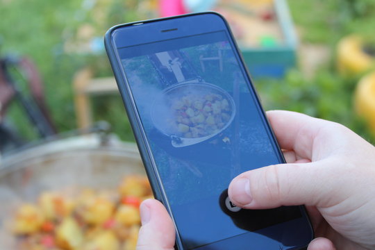Women`s hands hold the phone and take pictures of food