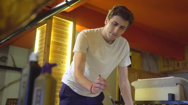 Young, caucasian man in a studio is busy working with a traditional Chinese huzhou brush