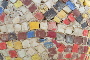 Colored bricks on the wall. Unusual mosaic on the fence. Decorated reinforced fence