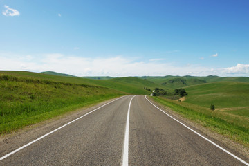 Beautiful summer landscape with a straight asphalt motorway going among green hills in a sunny day