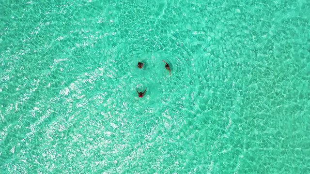 thailand top down aerial shot of 3 women swimming in the crystal clean ocean near tropical islands