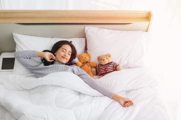 Asian woman sleeps on bed with two teddy bear..